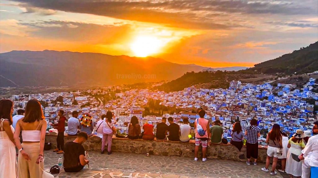 Tourists watching sunset over Chefchaouen Morocco from the Spanish Mosque viewpoint