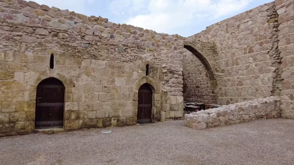 Ancient stone architecture featuring arched doorways and wooden doors inside the Aqaba Fort courtyard.
