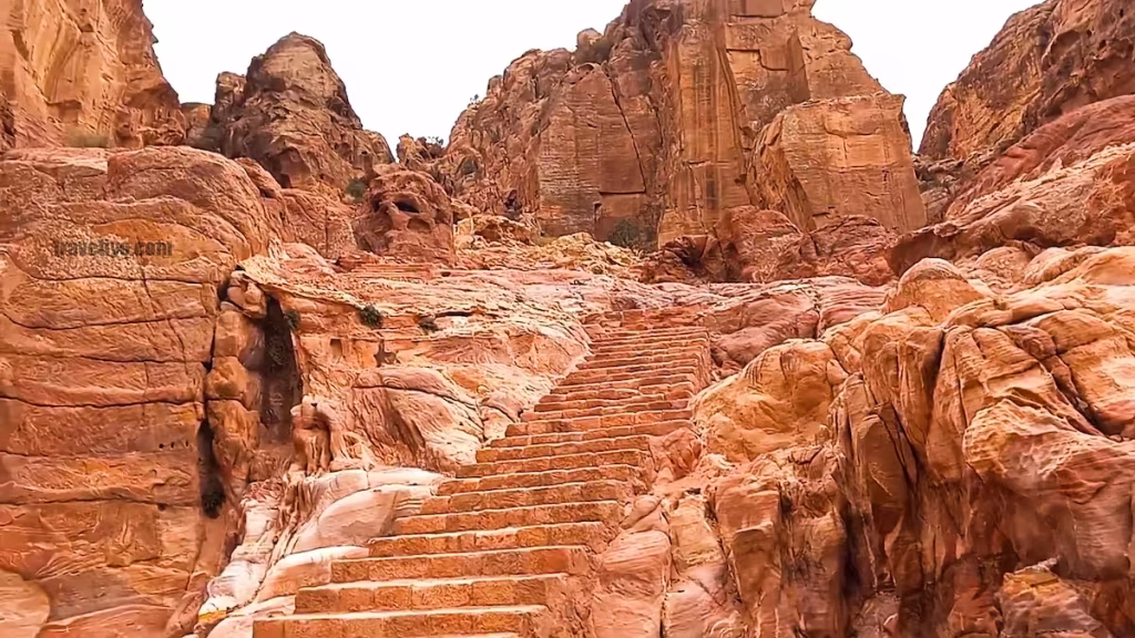 Ancient stone steps carved into the sandstone mountains leading up a rugged hiking trail in Petra.