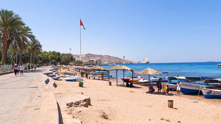 Panoramic view of Red Sea beaches in Aqaba with colorful boats moored on the sandy shore.
