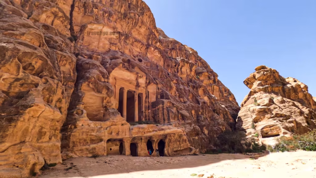 Elaborate rock-cut facades and ancient tomb entrances along the colorful cliffside in Petra.