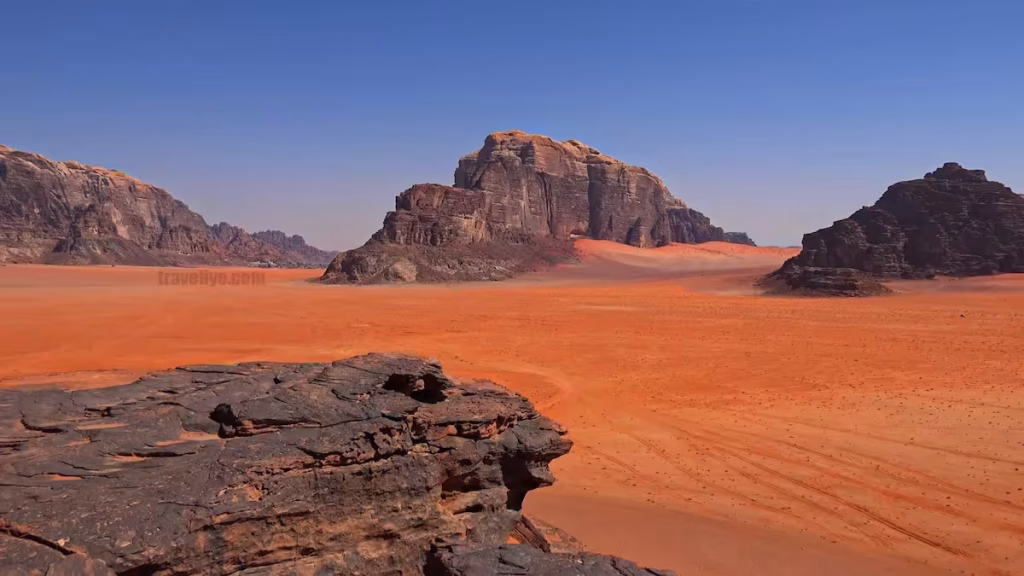 Vast red sand desert landscape with rugged granite mountains in Wadi Rum, Jordan.