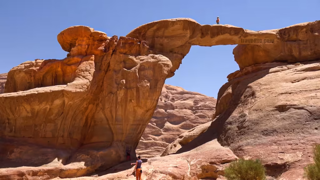 A natural sandstone arch against a clear blue sky in the Wadi Rum desert, Jordan.
