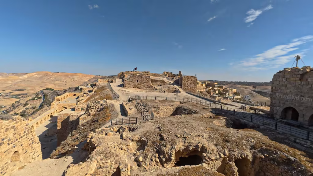 Wide expanse of the upper citadel grounds and ancient stone excavations under a bright blue sky at Al Karak castle in Jordan.