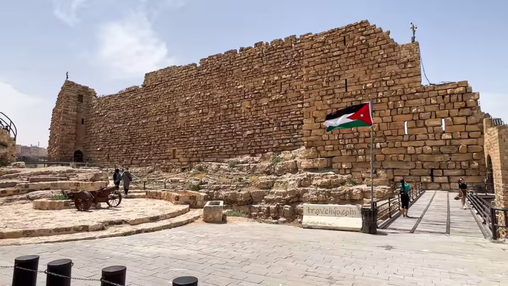 The main stone entrance bridge of Al Karak castle in Jordan with a Jordanian flag waving.
