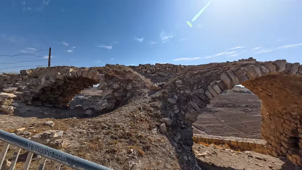 Large freestanding ancient stone arches framed against a clear blue sky at Karak Castle.