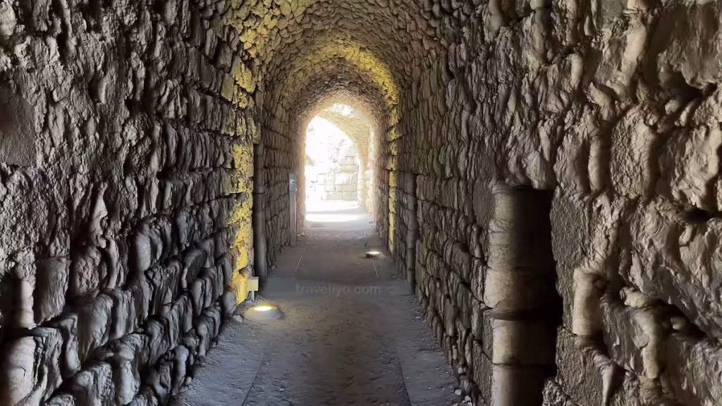 A long arched subterranean stone corridor with bright natural daylight shining through an exit tunnel at the karak castle in jordan.