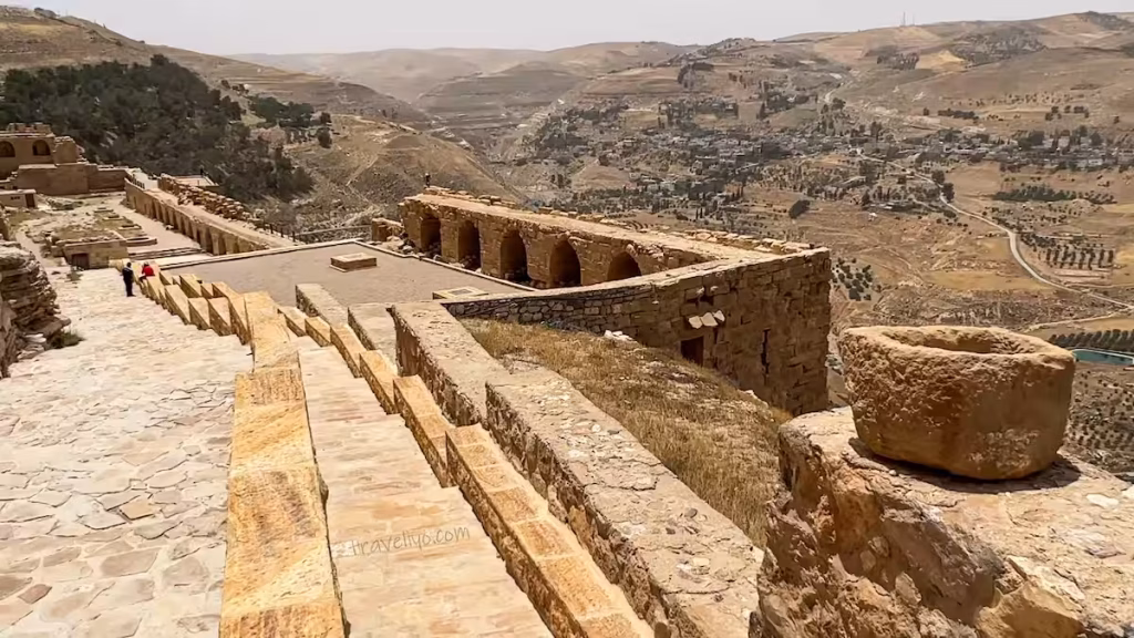 A long row of open vaulted stone galleries and rooms overlooking the mountain landscape at Karak Jordan castle.