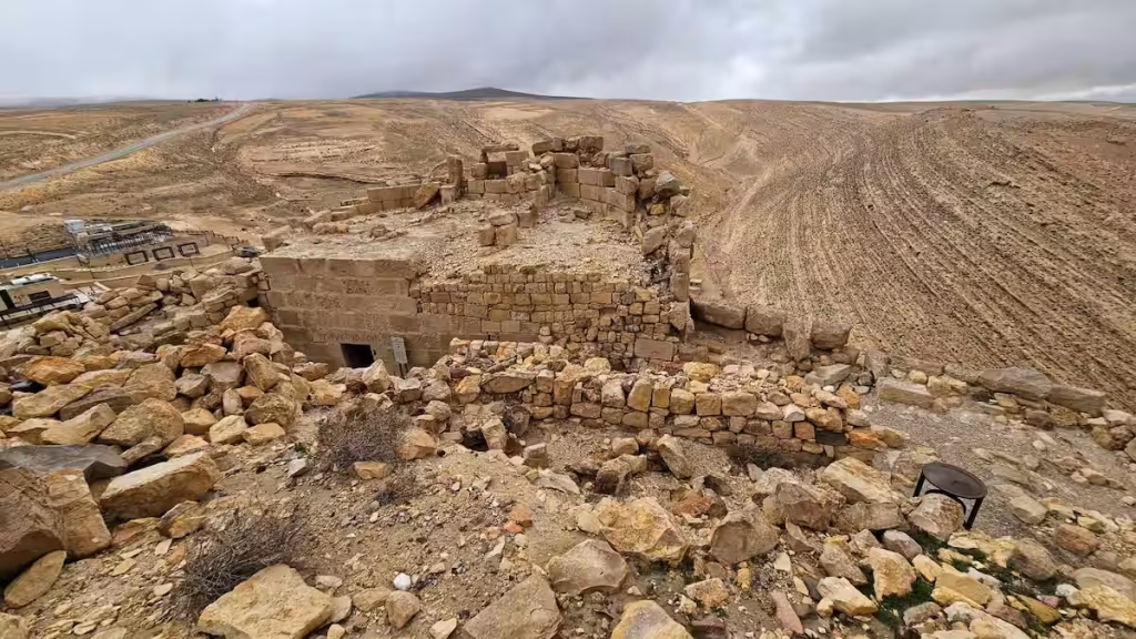 A bird's-eye view showing a ruined section of Shobak Castle in Jordan transitioning into the vast desert terrain.