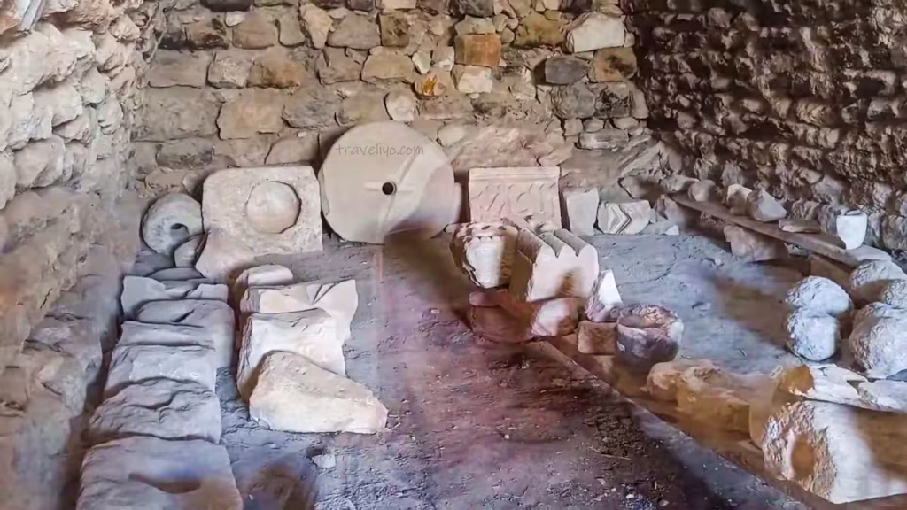 Ancient stone artifacts, including a round millstone and carved blocks inside Shobak Castle in Jordan.