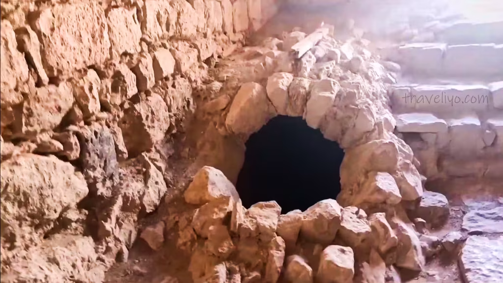 A circular stone opening or well leading into a dark tunnel at Shobak Castle in Jordan.