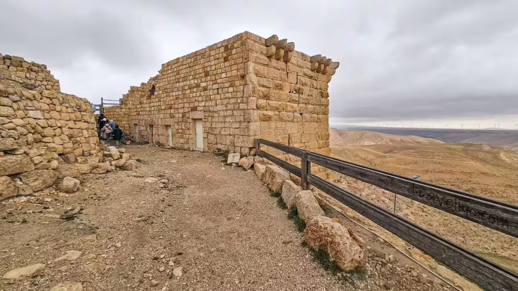 A well-preserved rectangular stone building and walkway at Shobak Castle in Jordan under an overcast sky.
