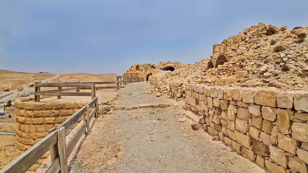 A tourist trail with a wooden safety fence winding through stone ruins at Shobak Castle in Jordan.
