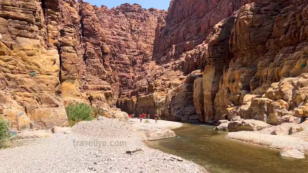 Hikers beginning their journey on the Wadi Mujib Siq Trail inside the wide canyon gorge.