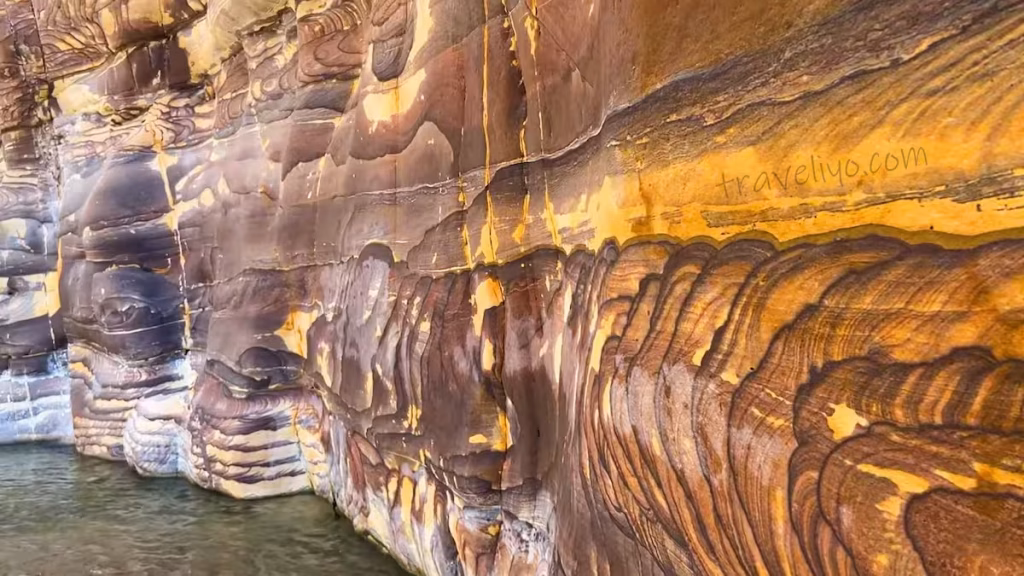 Close-up view of the unique swirled wave patterns and geological strata on the walls of Wadi Mujib canyon.