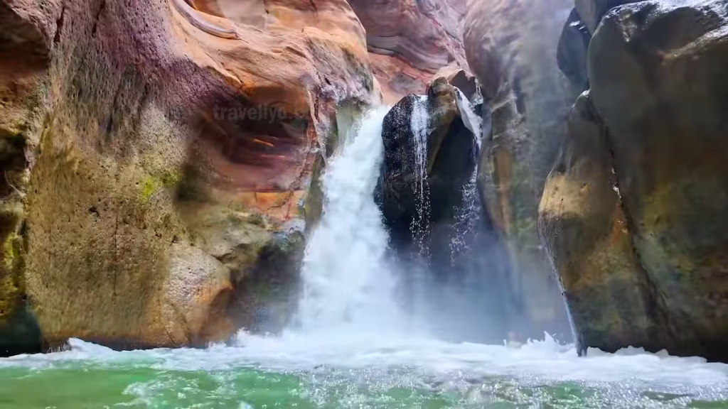 The spectacular final waterfall pouring into a pool at the end of the Wadi Mujib Siq Trail.