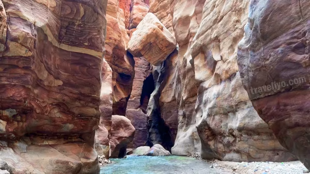 A giant boulder suspended and wedged between the narrow vertical walls of the Wadi Mujib Siq Trail.