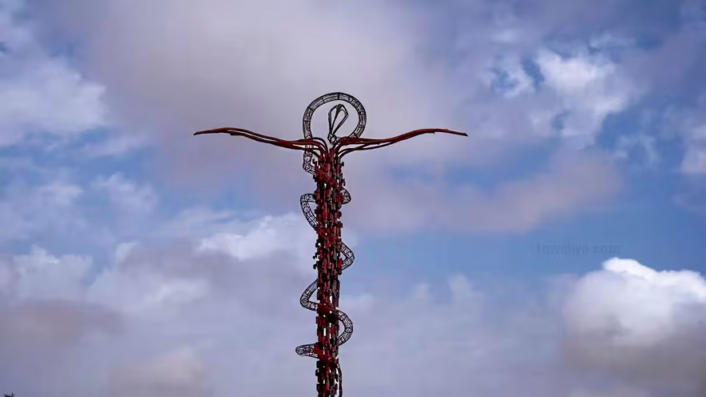The iconic Brazen Serpent Cross monument set against a cloudy blue sky at Mount Nebo.