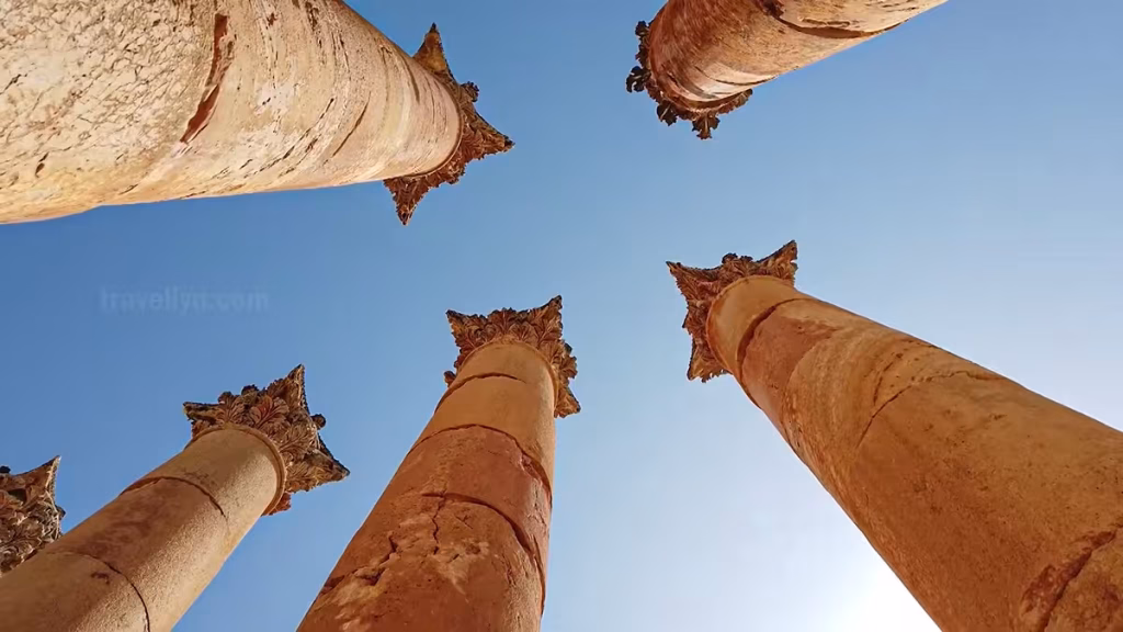 Low angle shot of Corinthian column capitals against blue sky in Jerash Jordan