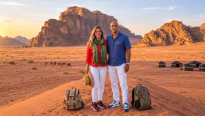 Couple with backpacks, sun hat, scarf and sneakers on a Wadi Rum sand dune at sunset, packing for Jordan